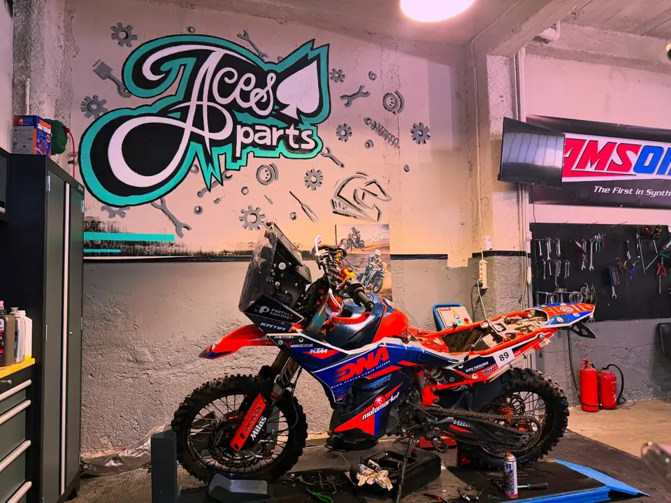 Το συνεργείο Aces Parts με το γκράφιτι του logo και μια adventure μοτοσυκλέτα στο ανυψωτικό